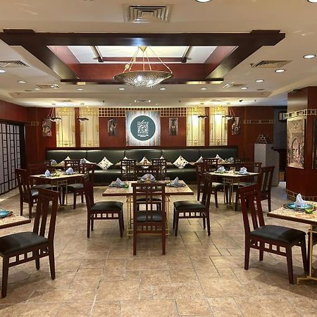 Safir Hotel Cairo Giza Екстериор снимка The photo shows the interior of a restaurant. The space features a combination of warm wood tones and elegant decorations. There are several dining tables arranged throughout, each set with plates, cutlery, and decorative napkins. The walls are adorn