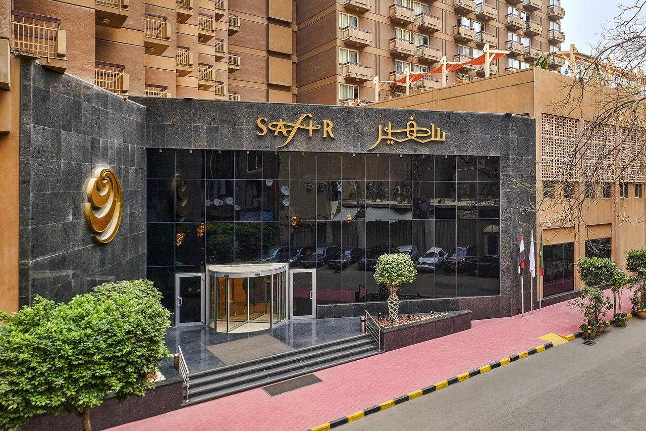 Safir Hotel Cairo Giza Екстериор снимка The photo depicts the entrance of a modern building, which appears to be a hotel or a commercial establishment. The facade features a large glass front with reflective surfaces. Above the entrance, there is a prominent sign displaying the name of the