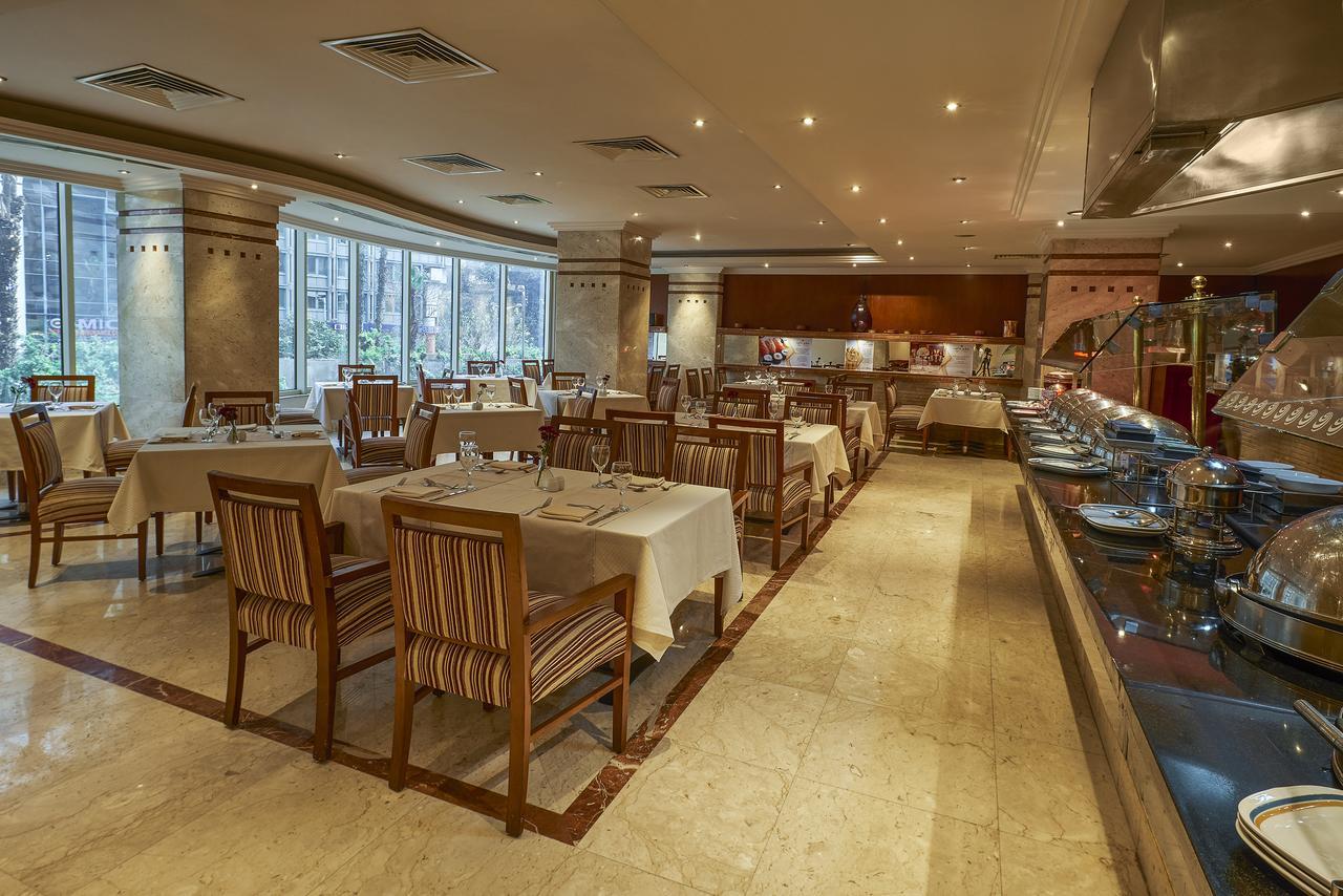 Safir Hotel Cairo Giza Екстериор снимка The photo shows the interior of a restaurant. It features a spacious dining area with several tables laid out with white tablecloths. The tables are accompanied by wooden chairs that have striped patterns. The restaurant is well-lit with soft lightin