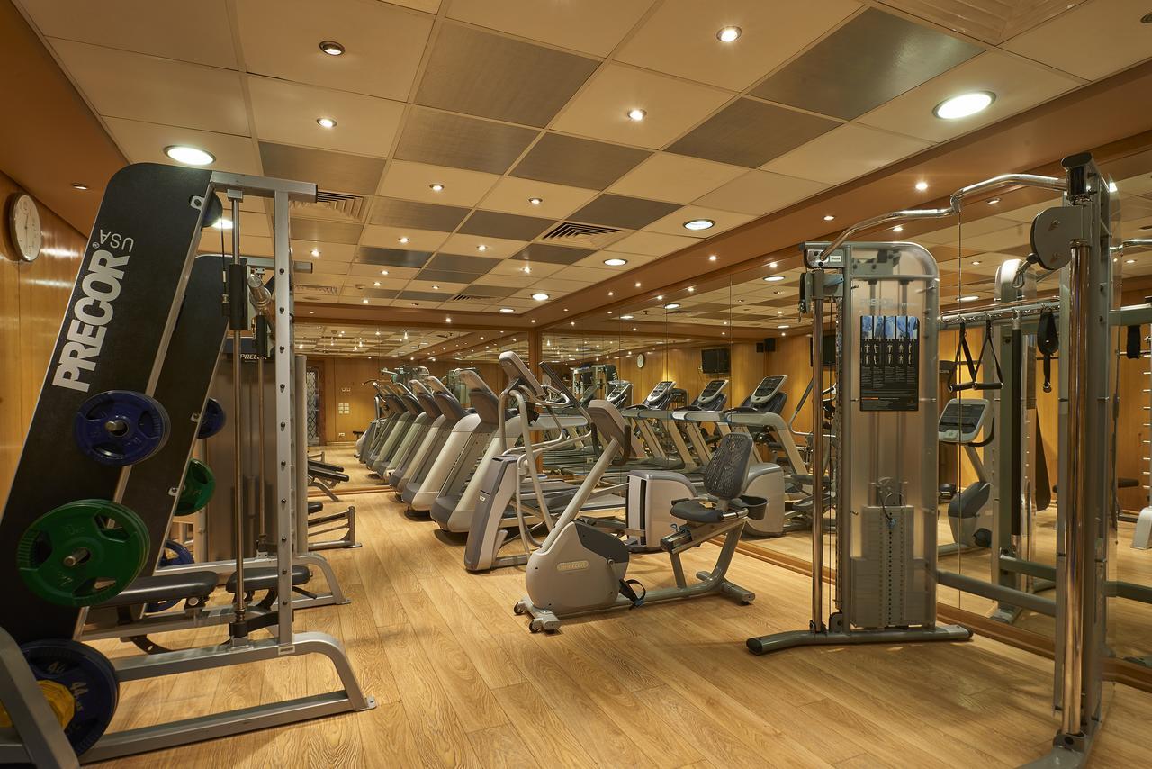 Safir Hotel Cairo Giza Екстериор снимка The photo shows a well-equipped gym with various exercise machines. There are several cardio machines lined up, including treadmills, stationary bikes, and elliptical trainers. Strength training equipment is also present, including a multi-functional